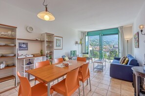 A modern kitchen with a dining area, a sofa, and a view of the city. - Appartement in Porlezza am Luganersee (Porlezza)
