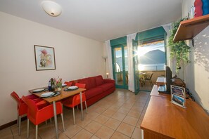 Ein kompakter Wohnbereich mit Essbereich, einem roten Sofa und Blick ins Freie.