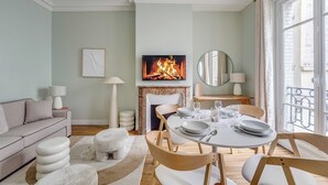 Een woonkamer met een open haard, een eettafel voor vier personen en een bank.