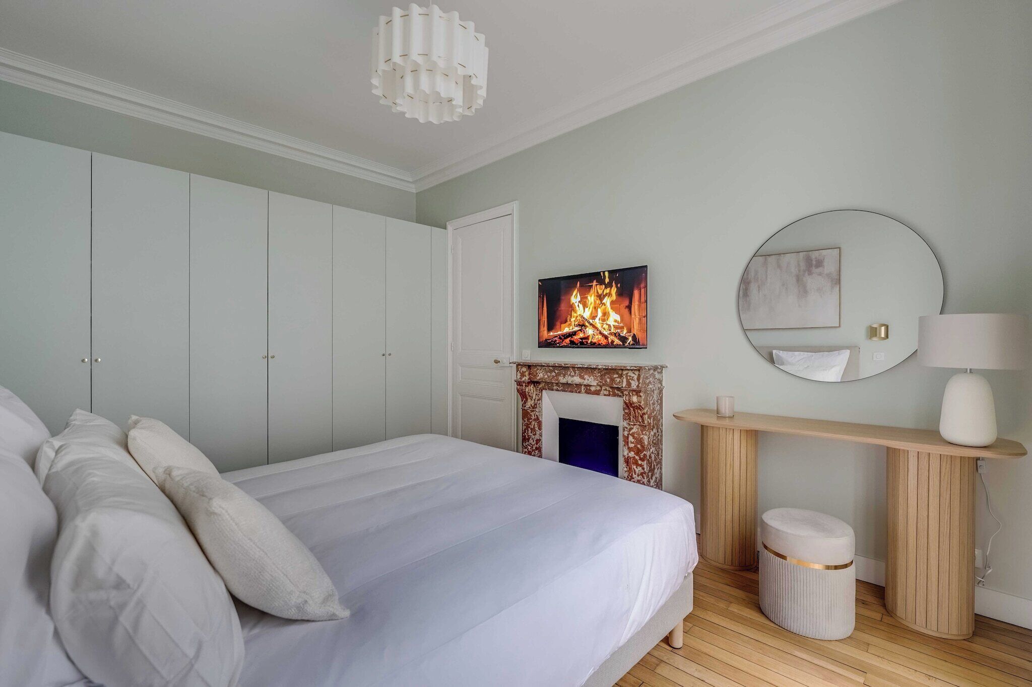 Une chambre à coucher avec un lit, une cheminée, un miroir et une lampe.