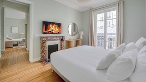 Een hotelkamer met een bed, een open haard, een televisie en uitzicht op een balkon.