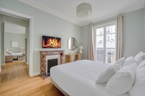 A hotel room with a bed, a fireplace, a television, and a balcony view. - Design Apartment 1BR/4P - Monceau (Paris)