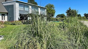 Een modern huis met twee verdiepingen, een grijze gevel en grote ramen.