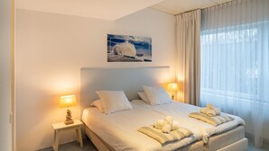 Een hotelkamer met een groot bed, twee bedlampjes, een schilderij aan de muur en een raam met gordijnen.