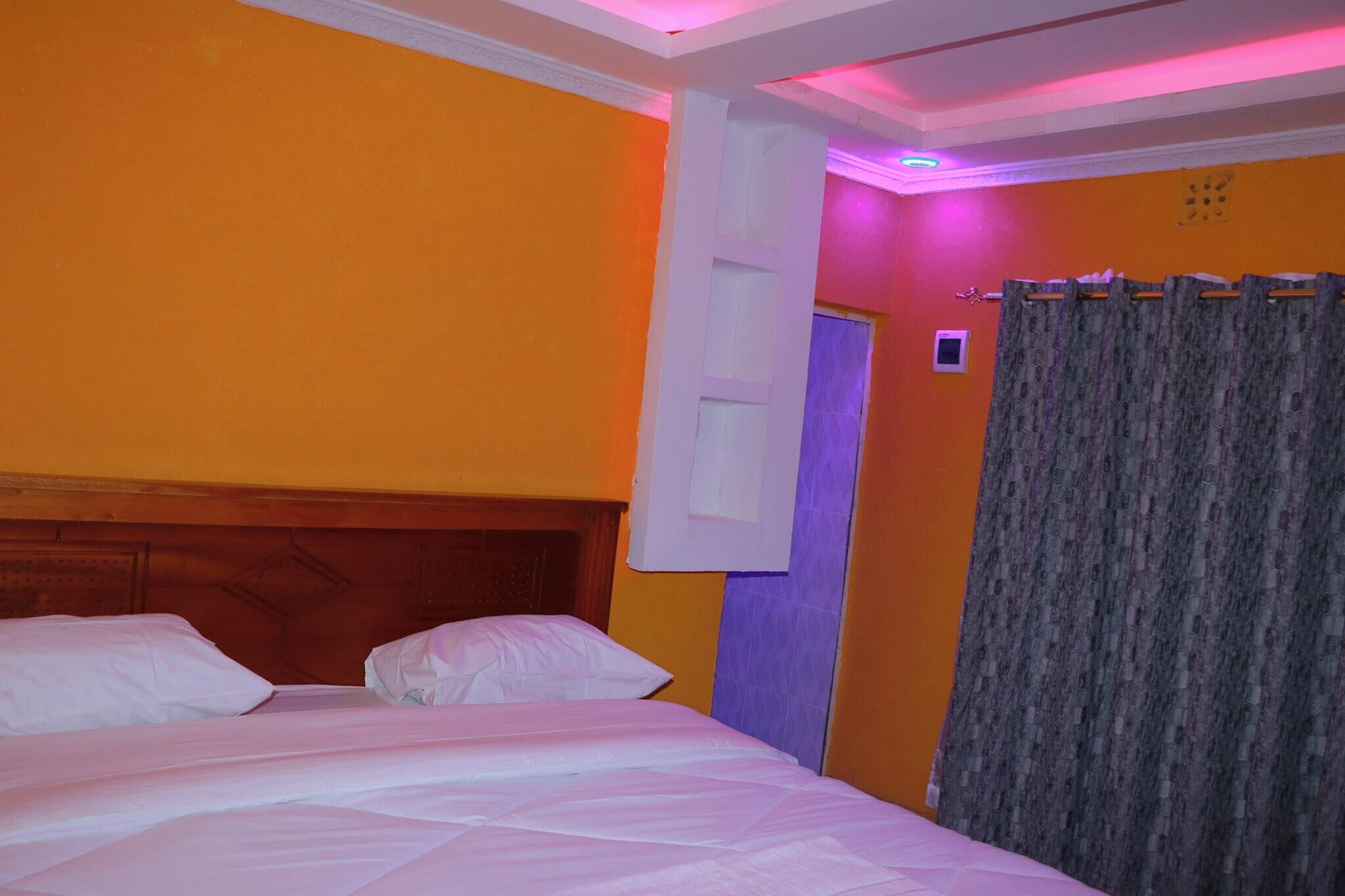 Una habitación de hotel con una cama, un cabecero de madera, una puerta con ventana y una cortina.
