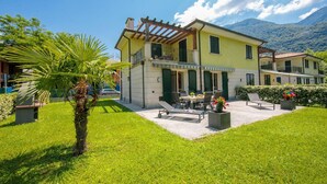 A two-story house with a patio area, a pergola, and a view of mountains. - Appartement mit Seeblick auf den Luganersee (Porlezza)