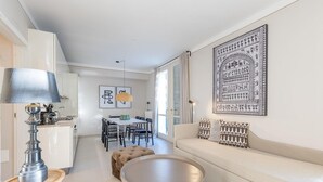 A modern living room with a sofa, a round coffee table, and a dining area with chairs and a table. - Appartement mit Seeblick auf den Luganersee (Porlezza)