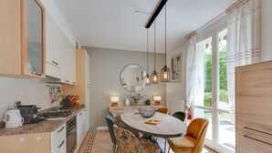 A modern kitchen with a round dining table, chairs, and a large mirror above. - Appartement mit Seeblick auf den Luganersee (Porlezza)