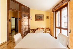 Ein Konferenzraum mit einem großen Tisch, weißen Stühlen, Holzsäcken und einem Gemälde an der Wand.