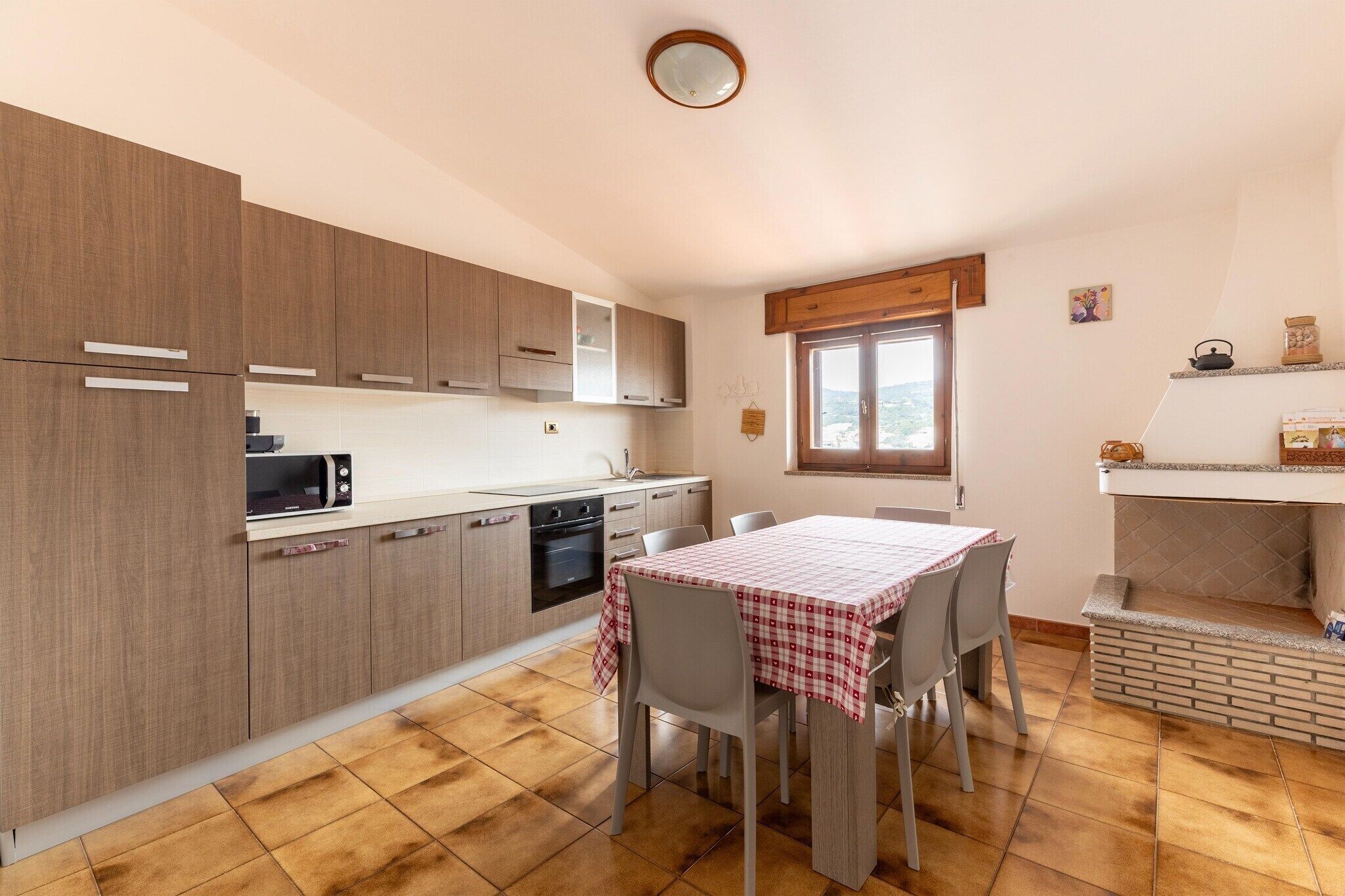 Cocina compacta con armarios de madera, un microondas, una estufa y una mesa de comedor con sillas.
