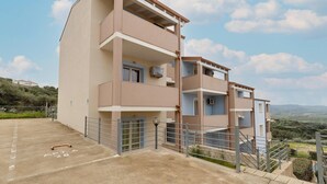 Un edificio residenziale a più piani con balconi, un'area di parcheggio e vista sulla campagna.