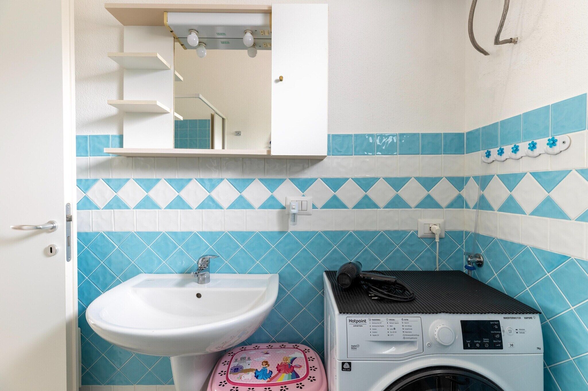 Un baño con lavamanos, lavadora y espejo.