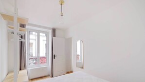 Et soveværelse med seng, garderobeskab, dør til en balkon og en hængende lampe.