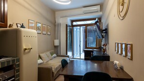 A compact hotel room with a kitchenette, a bed, a dining table, and a large window offering a view of the street. - Small oasis in the heart of Rome (Roma)