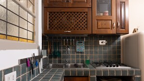 A compact kitchen with a built-in gas stove, a sink, and wooden cabinets. - Small oasis in the heart of Rome (Roma)