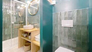 Moderni kylpyhuone, jossa on pyöreä peili, pesuallas ja wc-istuin.
