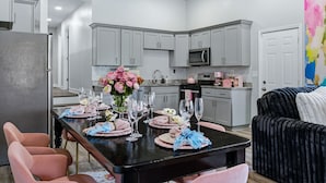 A modern kitchen with grey cabinets, a microwave, and a dining area with a black table set for a meal.