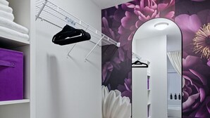 A bathroom with a mirror, a shower, and a floral wallpaper.