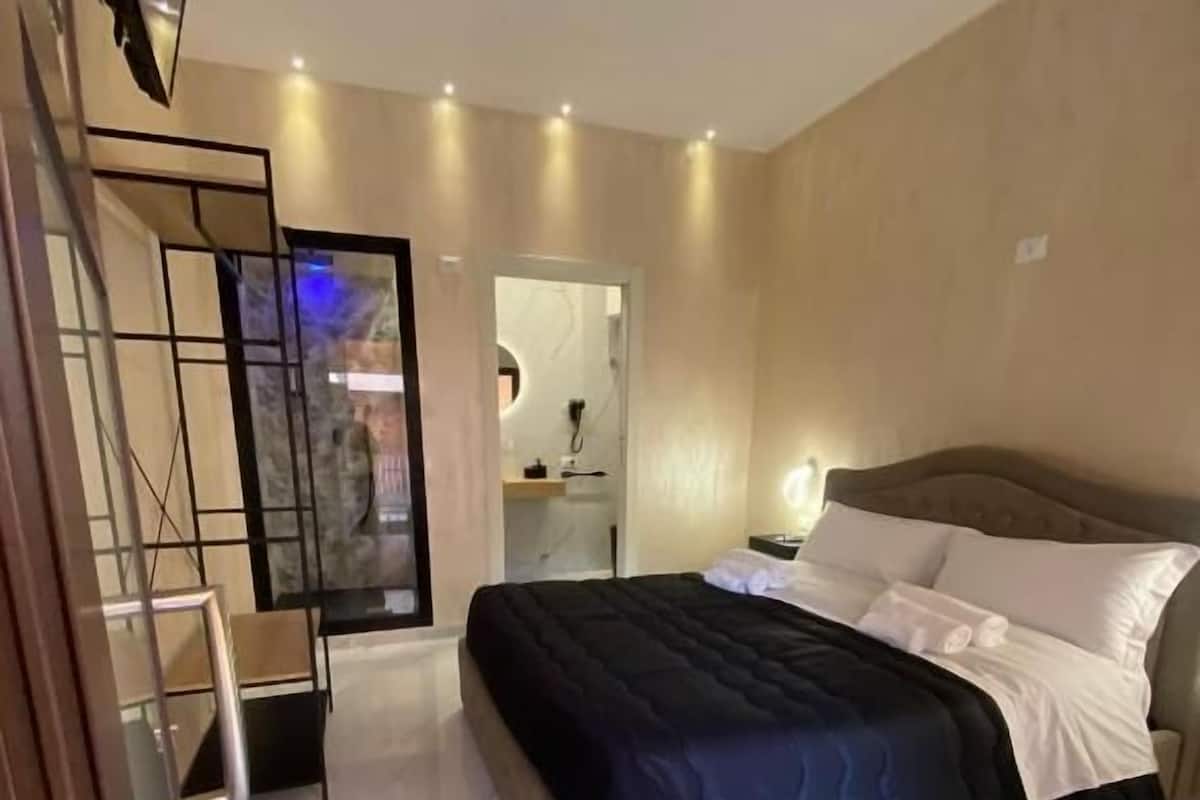 A modern bedroom with a bed, a desk, and a mirror.