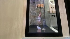 Un baño moderno con cabina de vidrio, suelo de mármol y zona de ducha visible.