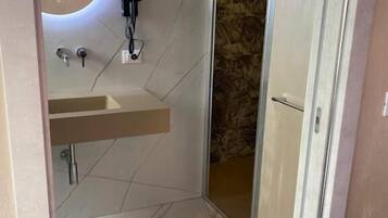 A modern bathroom with a marble floor, a sink with a mirror, and a shower area.