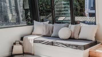 A cozy seating area with a cushioned bench, pillows, and a small table with a lamp.