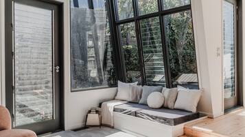 A modern interior with a built-in bench seating area, large windows, and a door with frosted glass panels.