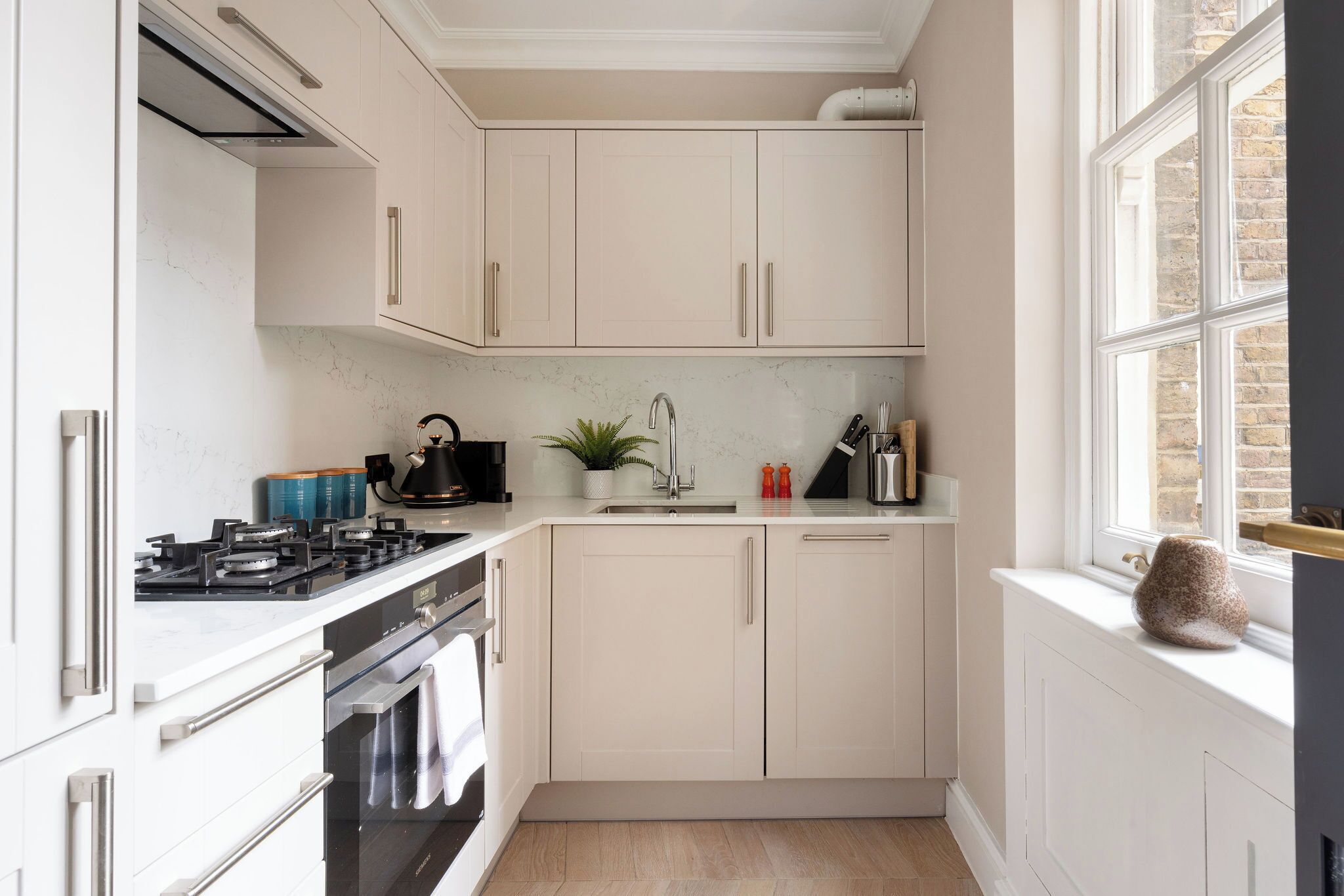 A modern kitchen with white cabinets, a gas stove, an oven, and a sink.