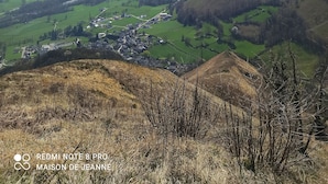 Una valle con un piccolo paese, campi verdi e montagne sullo sfondo.