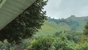 Un'area verde all'aperto con tavolo e sedie, un muro in pietra e vista su dolci colline sullo sfondo.