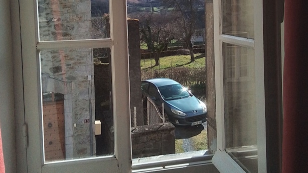 Una stanza con una grande finestra che offre vista su una catena montuosa e un'auto parcheggiata all'esterno.
