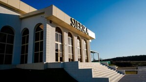 A building with the name 'SIERRA' on the facade, featuring a modern architectural style with arched windows and a staircase leading to the entrance. - Hotel Sierra (Pitesti)