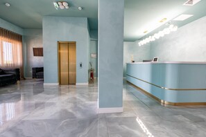 A modern lobby with a reception desk, a gold elevator, and a marble floor. - Hotel Sierra (Pitesti)