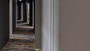A hallway with a patterned carpet, white walls, and a door at the end. - Hotel Sierra (Pitesti)