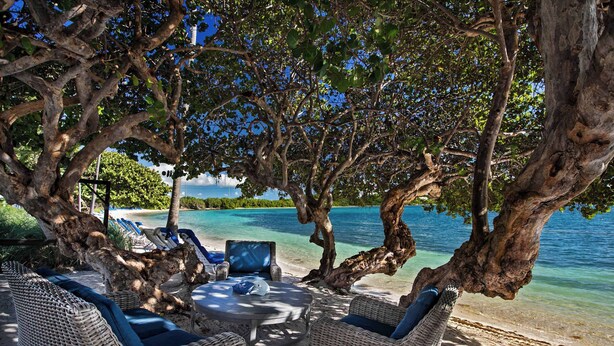 A beachside lounge with wicker furniture, a round table, and a hammock. - Ritz-Carlton Club® / 2 Bed Residence (East End)