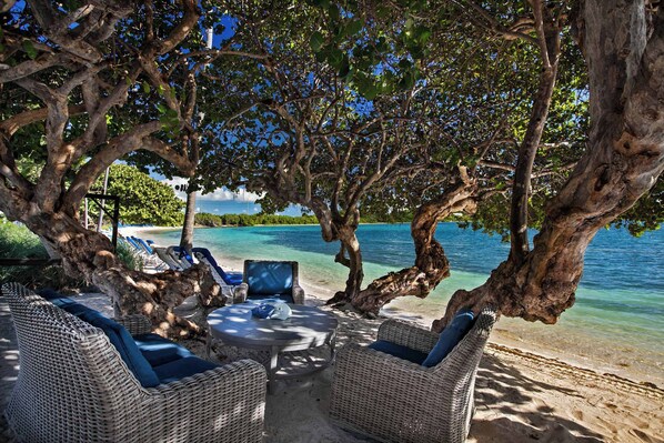 Eine Strandlounge mit Korbmöbeln, einem runden Tisch und einer Hängematte.