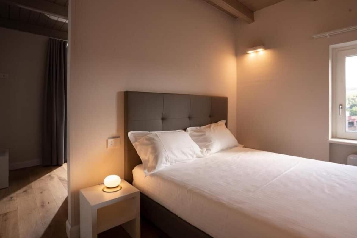 A bedroom with a bed, nightstand, and bedside lamp.