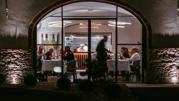 A restaurant with an arched entrance, tables, and chairs. - Vinea Relais (Dogliani)