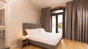 A bedroom with a bed, nightstand, and a view through a glass door. - Vinea Relais (Dogliani)