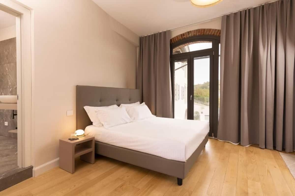 A bedroom with a bed, nightstand, and a view through a glass door.