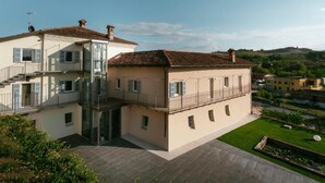 A two-story building with a glass entrance and a balcony. - Vinea Relais (Dogliani)