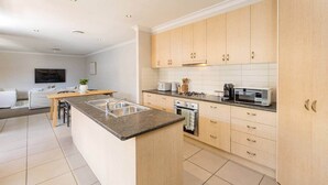 A modern kitchen with a central island, wooden cabinets, a built-in oven, and a microwave. - Mildura City Centre Escape 2 (Mildura)