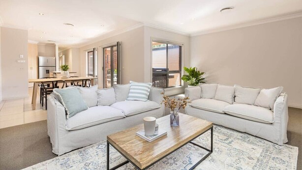 A modern living room with two sofas, a coffee table, and a dining area with a kitchen in the background. - Mildura City Centre Escape 2 (Mildura)