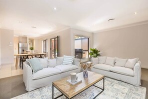 A modern living room with two sofas, a coffee table, and a dining area with a kitchen in the background. - Mildura City Centre Escape 2 (Mildura)