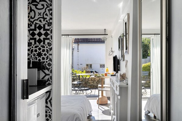 A bedroom with a bed, a desk, and a chair, a bathroom with a toilet and sink, and a balcony with a table and chairs.