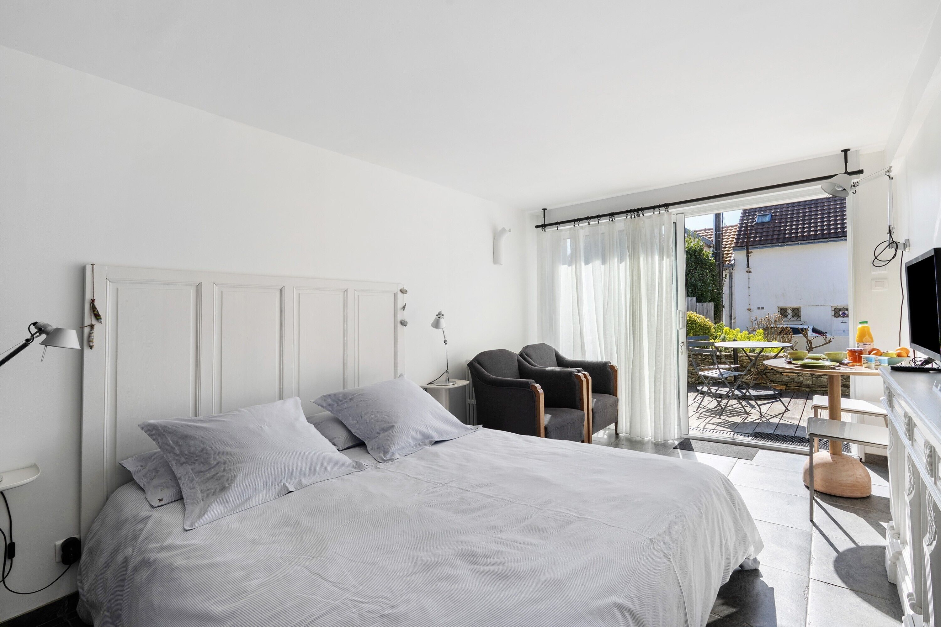 Une chambre à coucher avec un lit, deux chaises, une table et une vue sur l’extérieur.
