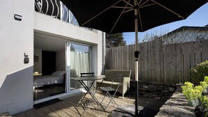 A modern outdoor patio with a table and chairs, a wooden deck, and a wooden fence.