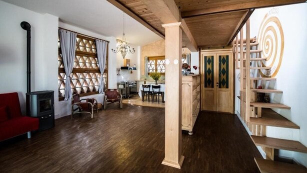 Ein geräumiger Wohnbereich mit Holzboden, einem roten Sofa, einem Kamin und einem Essbereich mit einer Chandeliebre.