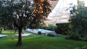 Ein Garten mit Schwimmbecken, Baum und Zelt.