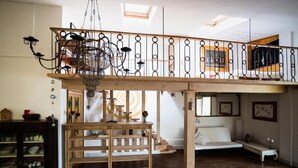 Ein Schlafzimmer im Loft-Stil mit Holzbalkendecke, einer Pendelleuchte und einem weißen Bett.